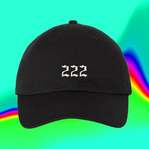 以下が含まれることがあります： ゴシック調のフォントで白く刺繍された数字「222」が特徴の黒い野球帽。この帽子は、構造化されたクラウン、湾曲したつば、中央上部にボタンを備えています。デザインは帽子のフロントパネルの中央に配置されています。