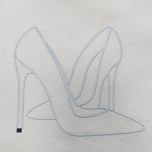 May include: Light blue embroidered design of two high-heeled shoes on a light gray fabric. The shoes are side by side, with pointed toes and thin heels. The embroidery thread is a lighter shade of blue, creating a delicate outline.