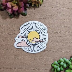 May include: White embroidered patch with a sun, clouds, and the text "I think it's time you had Pink Cloud Summer".