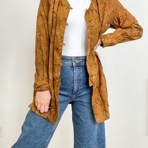 May include: A long-sleeved, brown patterned shirt with a button-up front. The shirt has a relaxed fit and is made of a lightweight fabric.