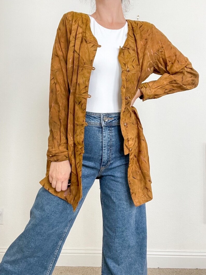 May include: A long-sleeved, brown patterned shirt with a button-up front. The shirt has a relaxed fit and is made of a lightweight fabric.