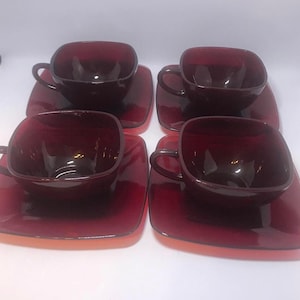 May include: Set of four square-shaped teacups and saucers in a deep burgundy red color. The cups and saucers are made of glass.