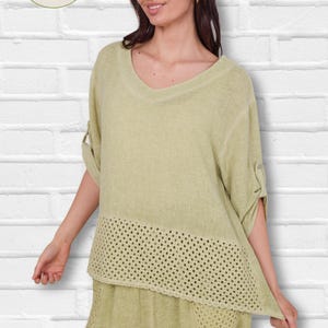 May include: Light green linen top and pants set. The top has a V-neck and a crocheted panel at the bottom. The sleeves are rolled up and buttoned. The pants have a matching crocheted pocket. The LaCapa Moda Italiana logo is in the upper left corner.