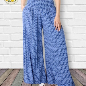 May include: Wide-leg pants in a blue and white geometric diamond pattern featuring a high, smocked elastic waistband and side pockets. The pants are paired with a plain white top. A circular logo in the corner displays the text LaCapa Moda Italiana.