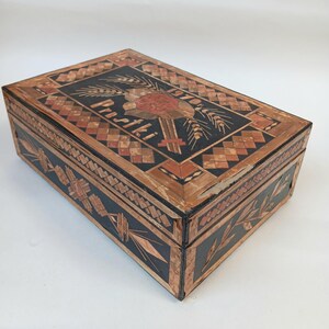 May include: A wooden box with intricate straw inlay designs. The top features a floral motif with wheat stalks and the text "1970 Prostk&iacute;".