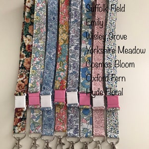 May include: Ten colourful patterned lanyards with silver clasps and plastic clips. The lanyards are arranged in a row from left to right. The text "From Left" is written above the lanyards, followed by a list of names for each lanyard: Peach Bloom, Suffolk Field, Emily, Wisley Grove, Yorkshire Meadow, Cosmos Bloom, Oxford Fern, Hyde Floral.