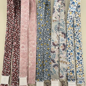 May include: Six colourful fabric lanyards with floral and paisley patterns. Each lanyard has a white plastic clip and a silver metal hook.