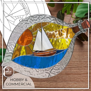 Può includere: Una scena di sole, barca a vela e oceano in vetro colorato all'interno di una bottiglia di vetro trasparente. La bottiglia è su una superficie di legno con piante verdi sullo sfondo. Il testo "HOBBY & COMMERCIAL" è nella parte inferiore dell'immagine.