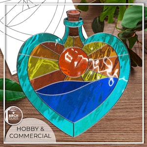 May include: A stained glass heart-shaped bottle with a cork stopper. The bottle is filled with a blue liquid and has a red, orange, and yellow design.