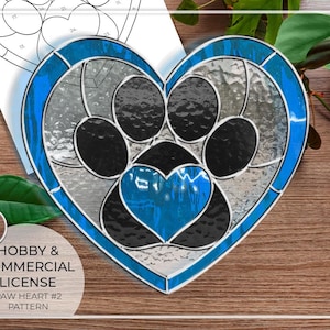 May include: A stained glass pattern of a blue heart with a paw print inside. The paw print is black and white with a smaller blue heart in the center. The pattern is labeled "Paw Heart #2 Pattern".