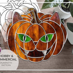 May include: Stained glass pattern of a pumpkin with a cat face. The pumpkin is orange with green eyes and a black nose. The pattern is labeled "Hobby & Commercial Pumpkitty Pattern".