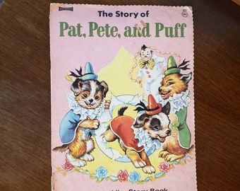 Op de afbeelding: Een roze en wit kinderboek met de titel "The Story of Pat, Pete, and Puff" met een illustratie van drie honden die verkleed zijn als clowns. Het boek is een linnenachtig verhalenboek.