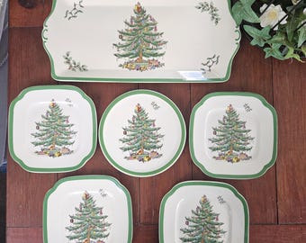 May include: A set of six vintage Christmas tree plates in a white and green color scheme. The plates feature a green Christmas tree with red and gold ornaments. The plates are perfect for serving holiday snacks or desserts.