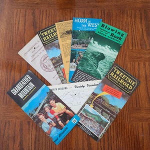 May include: A selection of vintage travel brochures from North Carolina, showcasing scenic attractions and historical sites. The brochures feature colourful images and text, including "Tweetsie Railroad" and "Blowing Rock."