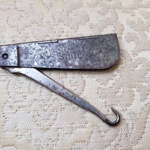 May include: A vintage metal shoe horn with a folding handle. The handle has the words "Talk Over Shoe" engraved on it.