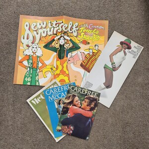 May include: A collection of vintage sewing pattern booklets and advertisements. The main advertisement reads "Sew it yourself with Cannon Towels and Sheets." Other booklets include "Carefree" and "McCall's" patterns. The image has a retro aesthetic.