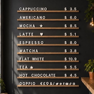 Könnte beinhalten: Eine Wandmenütafel mit horizontalen Holzregalen und weißen Buchstabenplättchen, die Kaffeegetränke und Preise anzeigen. Das Menü listet Cappuccino, Americano, Mocha, Latte, Espresso, Matcha, Flat White, Tea und Hot Chocolate auf.