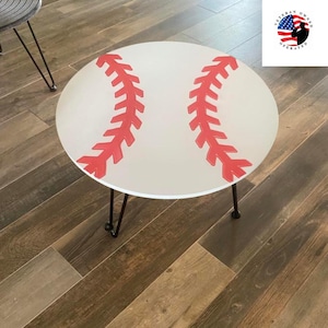 May include: A white round table with a baseball design. The table has red stitching and black hairpin legs.