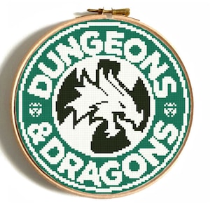 May include: A green and white cross-stitch embroidery hoop with the text "Dungeons & Dragons" and a black and white dragon logo in the center.