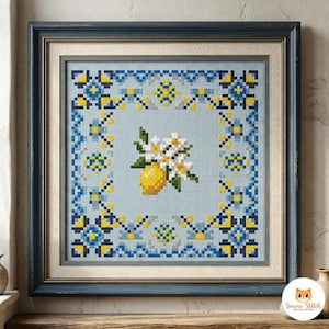 Pode incluir: Obra de arte em ponto cruz emoldurada com um limão e flores brancas. O design é definido contra um fundo azul claro com uma borda de padrões geométricos azuis e amarelos. A moldura é azul escuro.