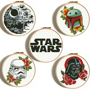 Pode incluir: Cinco aros de bordado com padrões de ponto cruz com tema Star Wars. Os aros representam Darth Vader, Boba Fett, um Stormtrooper, a Estrela da Morte e as palavras "Star Wars".