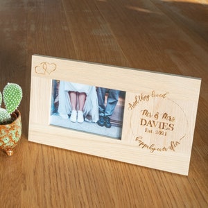 May include: A light wood photo frame with two openings for photos. The frame is engraved with the text "And they lived happily ever after" and "Mr. & Mrs. Davies Est. 2021".
