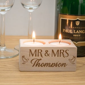 May include: A wooden candle holder with two tea lights burning. The holder is engraved with "MR & MRS Thompson" and two doves.