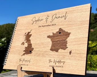 May include: A wooden guest book with a spiral binding. The cover features a map of the United Kingdom and France with the text "Sophie & Daniel" and "21st September 2024". The text "The Proposal" and "The Wedding" are also included with the locations "LONDON, UK" and "PARIS, FRANCE".