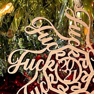 May include: A wooden Christmas ornament shaped like a bird with the words "Fuck this Christmas" written on it.