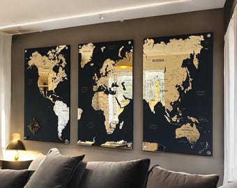 May include: Three black framed world maps with gold foil accents. The maps are mounted on a wall in a living room setting.