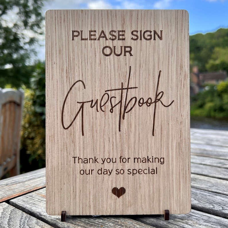 May include: Wooden sign with the text "Please sign our Guestbook" and "Thank you for making our day so special" with a small heart at the bottom.