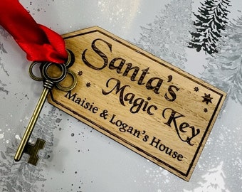 May include: A wooden key tag with the text "Santa's Magic Key" and "Maisie & Logan's House" in a cursive font. The tag is attached to a vintage-style key with a red ribbon.