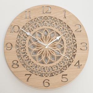 May include: A wooden wall clock with a decorative, laser-cut mandala design. The clock face features Roman numerals and a silver-toned hour and minute hand.