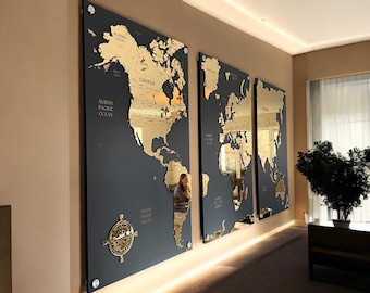 Könnte beinhalten: Ein dreiteiliges Wandbild-Set mit einer goldfarbenen Weltkarte auf schwarzem Hintergrund. Die Karten sind in einem schwarzen Rahmen gerahmt und an einer Wand mit einem Lichtstreifen dahinter montiert.