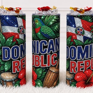 May include: Three cylindrical tumblers featuring a sparkling rhinestone design. The graphics include the Dominican Republic flag, a green parrot, a drum, and red hibiscus flowers. The text DOMINICAN REPUBLIC is displayed in bold, blue and red letters.