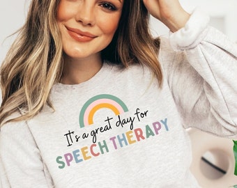 May include: A gray sweatshirt with a rainbow graphic and the text "It's a great day for SPEECH THERAPY".