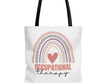 May include: A white tote bag with black handles features a pink, purple, and gray rainbow with a red heart in the center. The text "OCCUPATIONAL therapy" is printed below the rainbow.