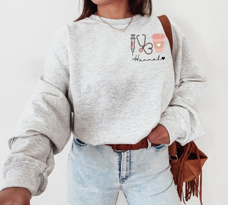 May include: Gray sweatshirt with a graphic of a syringe, stethoscope, coffee cup, and the text "Hannah".