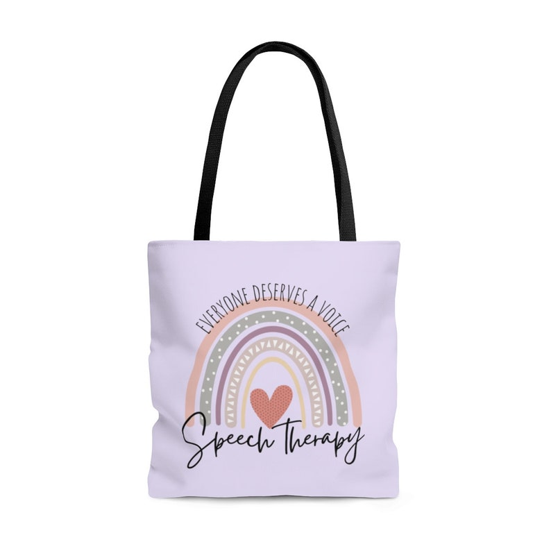 May include: A light purple tote bag with black handles. The bag features a rainbow with a heart in the center and the text "Everyone deserves a voice" above the rainbow and "Speech Therapy" below the rainbow.