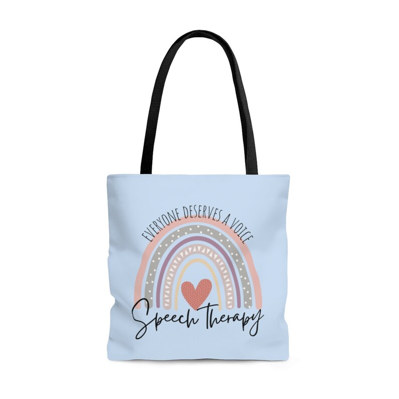 May include: A light blue tote bag with black handles. The bag features a rainbow with a heart in the center and the text "Everyone deserves a voice" above the rainbow and "Speech Therapy" below the rainbow.
