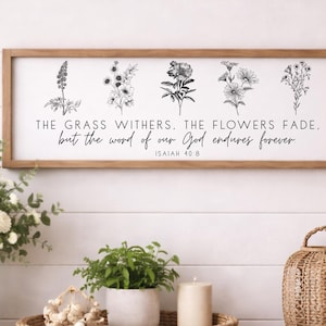 May include: A wooden framed sign with the text "THE GRASS WITHERS. THE FLOWERS FADE. but the word of our God endures forever. ISAIAH 40:8" above floral illustrations. The sign is displayed above a wooden table with decorative items.