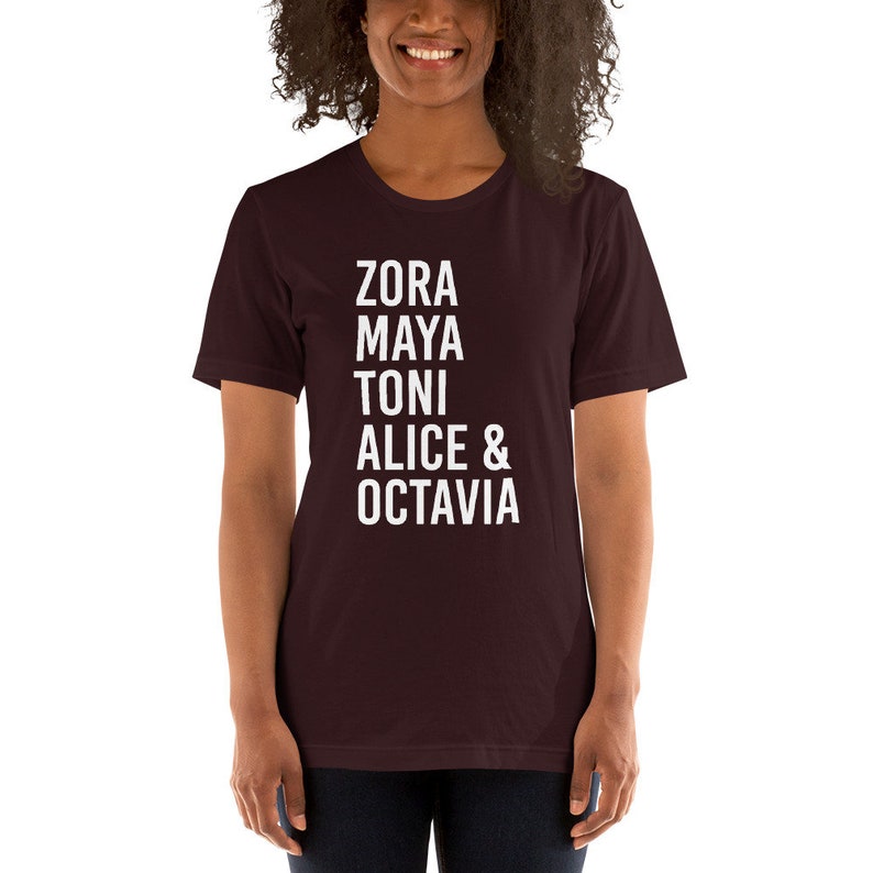 May include: A maroon t-shirt with white text that reads "Zora Maya Toni Alice & Octavia".