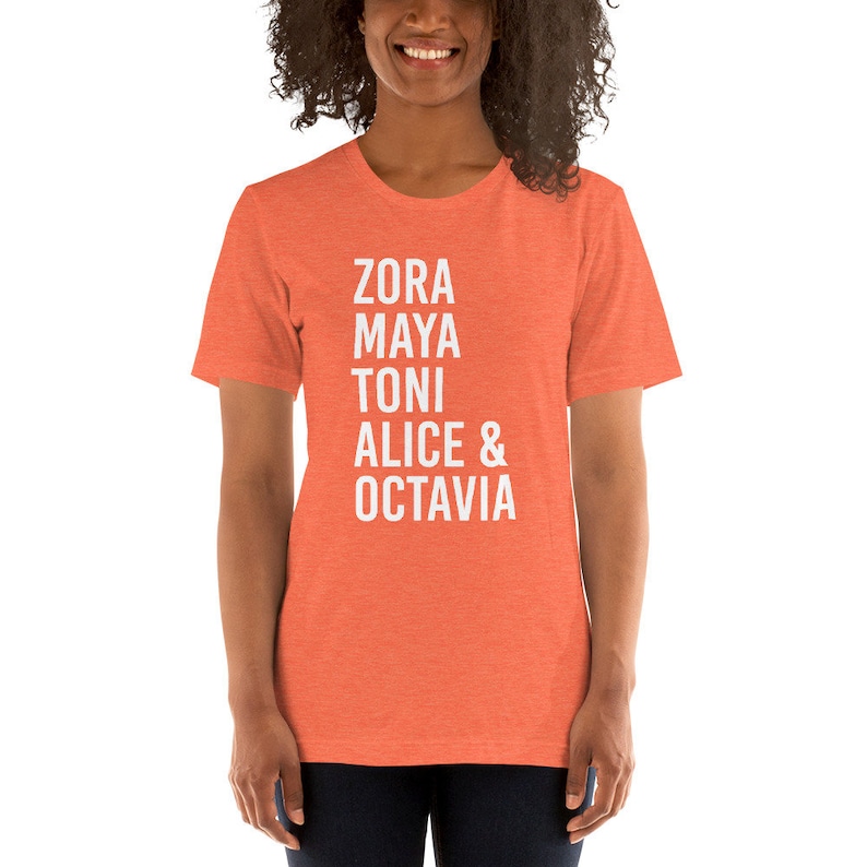 May include: A coral-colored t-shirt with the names Zora, Maya, Toni, Alice & Octavia printed in white.