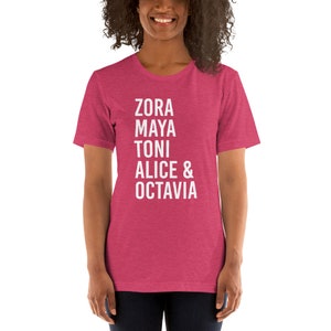 May include: A pink heather t-shirt with white text that reads "Zora Maya Toni Alice & Octavia".