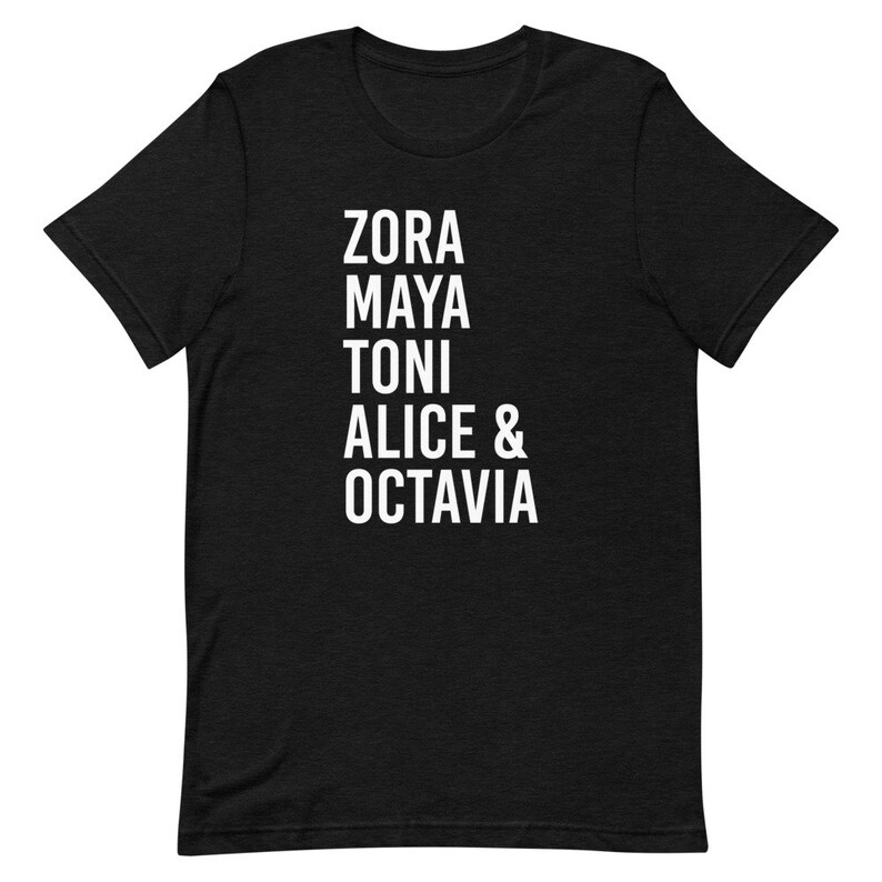May include: Black t-shirt with white text that reads "Zora Maya Toni Alice & Octavia"