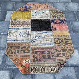 Puede incluir: Una alfombra de patchwork colorida con una variedad de patrones geométricos y diseños en tonos de rojo, azul, amarillo y marrón. La alfombra está hecha de materiales reciclados y tiene un aspecto único y tejido a mano.