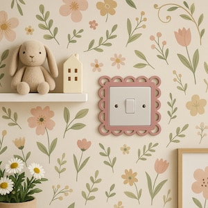 May include: A light pink, scalloped-edge light switch cover with a white switch. The wall features a floral wallpaper design with flowers and leaves in soft pink, yellow, and green tones. A stuffed bunny and house are on a shelf.