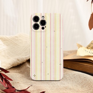May include: A phone case with a vertical striped pattern in pastel yellow, pink, and white. The case has a camera cutout with three lenses and a flash. Small star-shaped designs are scattered across the surface.