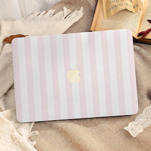 Op de afbeelding: Een laptophoesje met een verticaal roze en wit gestreept patroon. Het Apple-logo is in het midden zichtbaar. De hoes ligt op een getextureerd oppervlak met andere decoratieve items.