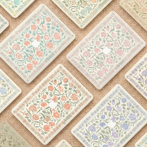 Op de afbeelding: Een collectie rechthoekige laptopskins met diverse bloemmotieven in zachte pastelkleuren zoals roze, blauw, geel en groen. Elke skin heeft een centrale uitsparing voor het Apple-logo en een decoratieve rand rondom het bloemmotief.
